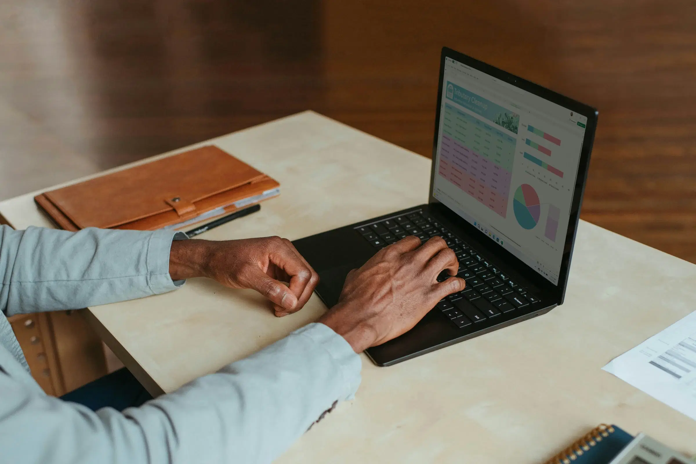 A person at a desk working on a laptop showing a reports dashboard