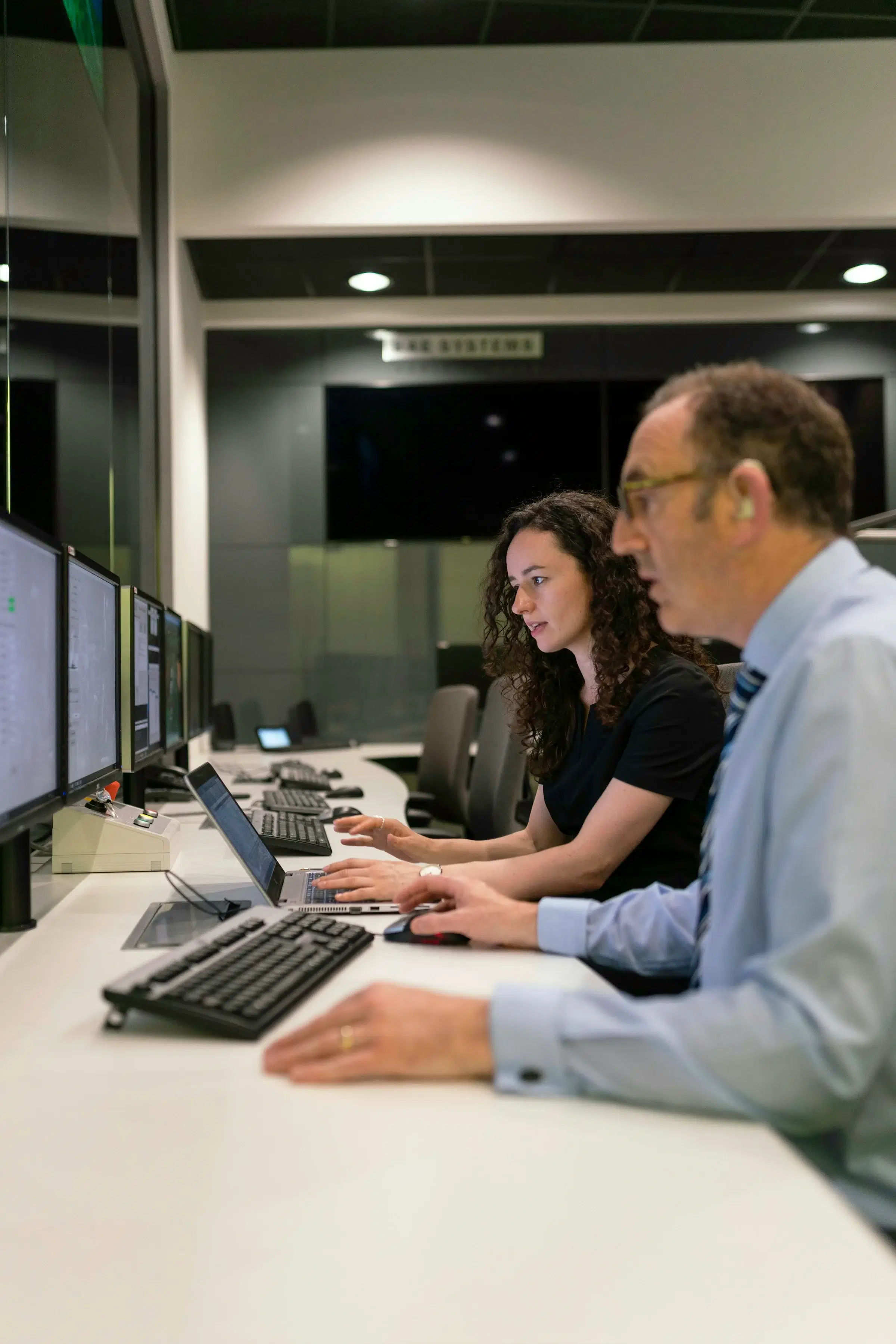 Two analysts at a long bank of monitors in an operations room